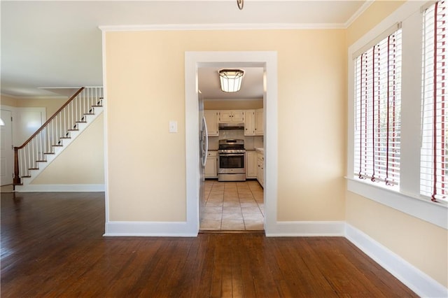 hall featuring stairway, baseboards, ornamental molding, and wood-type flooring