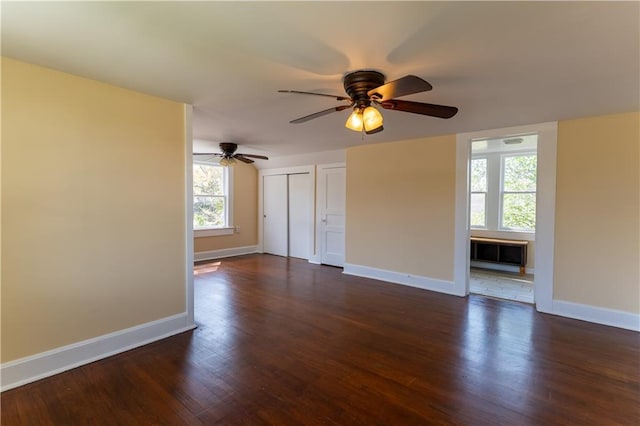 empty room featuring baseboards, a ceiling fan, and dark wood-style flooring