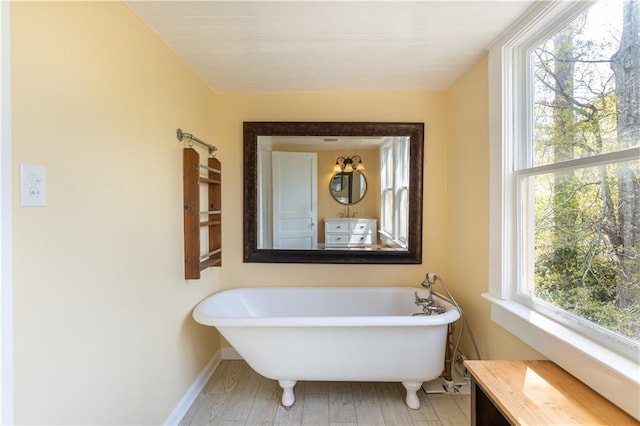 full bathroom with a freestanding tub and baseboards