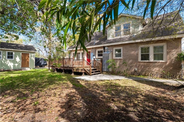 rear view of house featuring brick siding, a patio area, a yard, and a deck