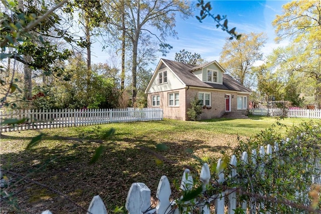 view of home's exterior featuring brick siding, a lawn, and fence private yard