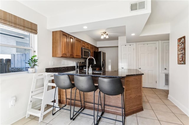6720 Argonne Boulevard ., New Orleans, LA 70124 - kitchen featuring a peninsula, brown cabinets, dark stone countertops, appliances with stainless steel finishes, and light tile patterned floors