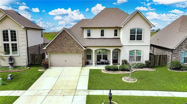 view of front of house with a front yard, fence, roof with shingles, stucco siding, and concrete driveway