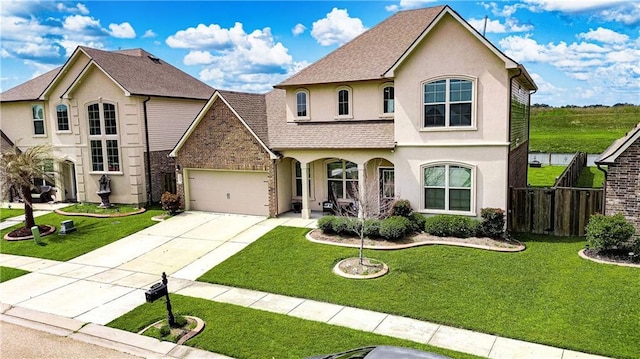view of front of home with fence, driveway, stucco siding, a front lawn, and a garage
