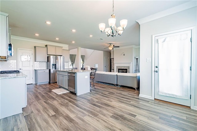 kitchen featuring ornamental molding, gray cabinets, backsplash, open floor plan, and appliances with stainless steel finishes