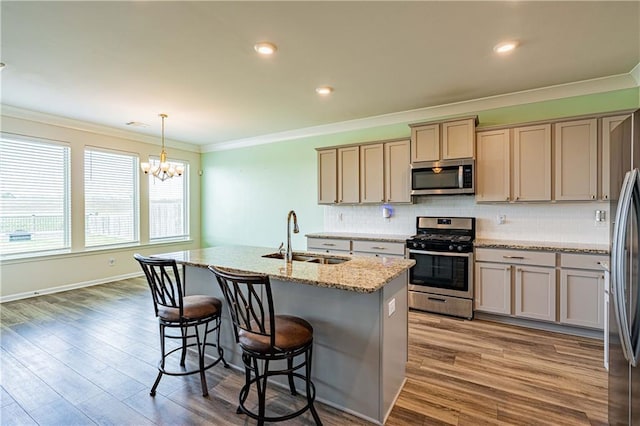 kitchen with backsplash, crown molding, wood finished floors, stainless steel appliances, and a sink