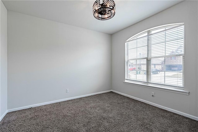 spare room featuring carpet, baseboards, and a chandelier