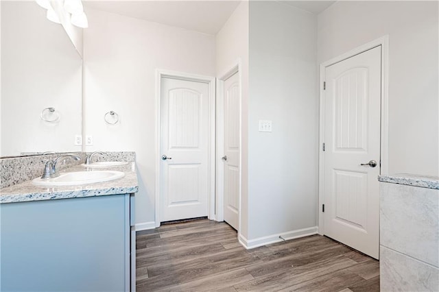 full bathroom with double vanity, wood finished floors, baseboards, and a sink