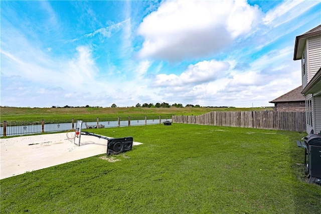 view of yard with a patio, a water view, and fence