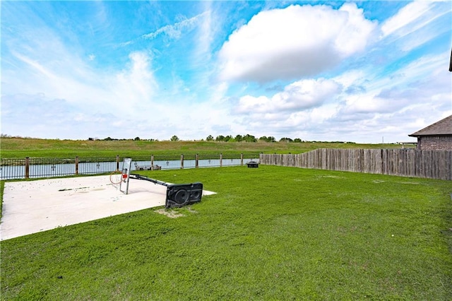 view of yard with a patio, fence, and a water view