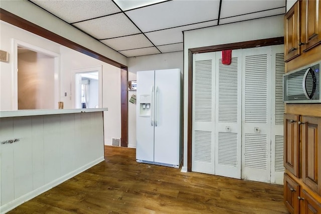 kitchen with dark wood-style floors, visible vents, a drop ceiling, white refrigerator with ice dispenser, and brown cabinets