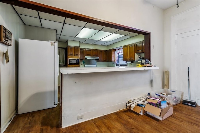 kitchen with under cabinet range hood, light countertops, freestanding refrigerator, and built in microwave