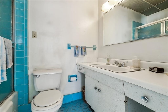 full bath featuring tile patterned flooring, toilet, vanity, and shower / bath combination with glass door