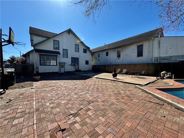 rear view of house with an outdoor pool, a patio, and fence