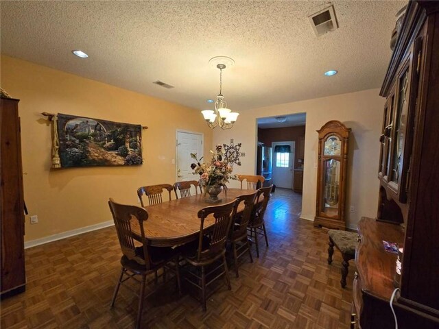 dining area with a textured ceiling, baseboards, visible vents, and a chandelier