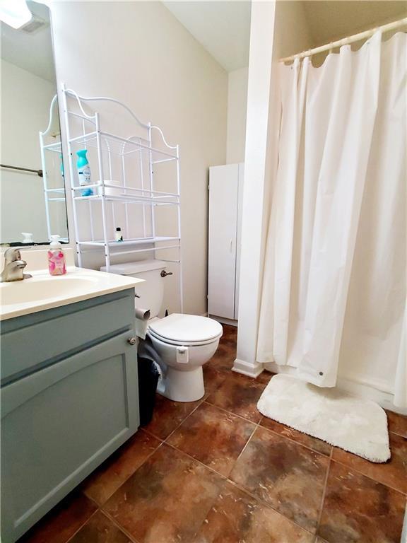 20996 Diversion Canal Rd, Saint Amant, LA 70774 - full bathroom featuring vanity, a shower with shower curtain, toilet, and tile patterned flooring