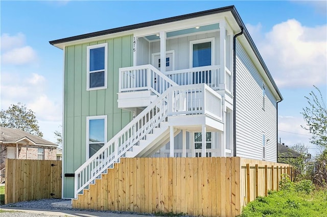 view of front of home featuring board and batten siding, fence, and stairs