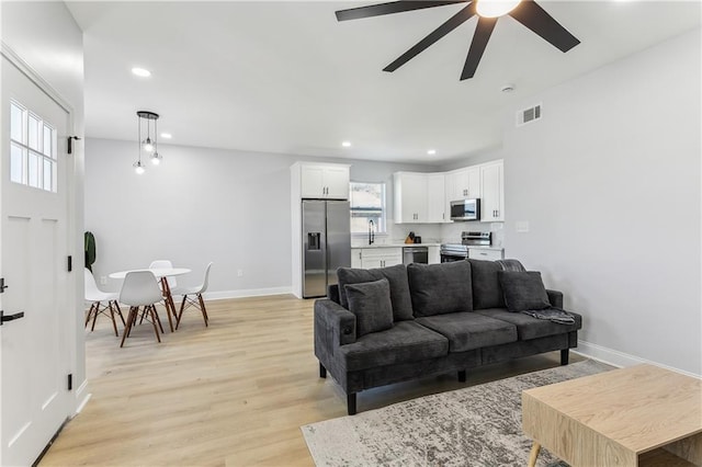 living room with baseboards, a ceiling fan, visible vents, and recessed lighting