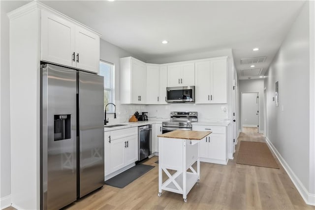 1413 Gordon St, New Orleans, LA 70117 - kitchen featuring appliances with stainless steel finishes, a sink, white cabinets, light wood-style flooring, and recessed lighting