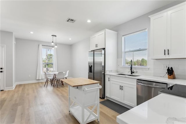 1413 Gordon St, New Orleans, LA 70117 - kitchen with appliances with stainless steel finishes, a sink, white cabinets, light wood finished floors, and recessed lighting