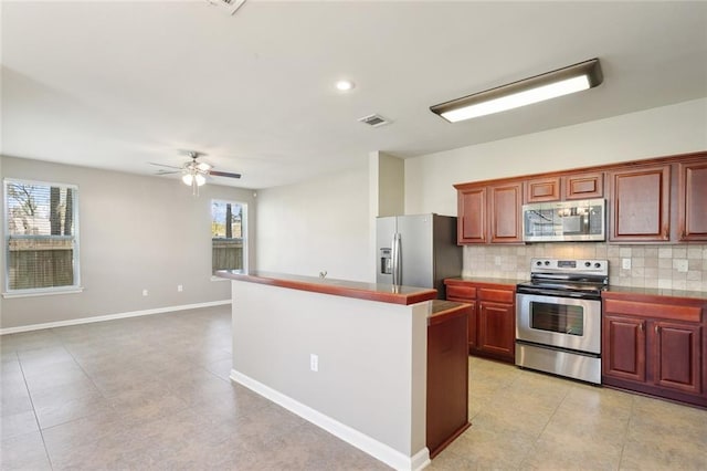 kitchen featuring baseboards, a ceiling fan, visible vents, decorative backsplash, and appliances with stainless steel finishes