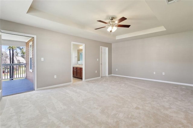 unfurnished bedroom featuring access to outside, connected bathroom, light carpet, a raised ceiling, and baseboards
