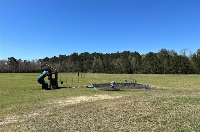 exterior space with a lawn, a forest view, and playground community