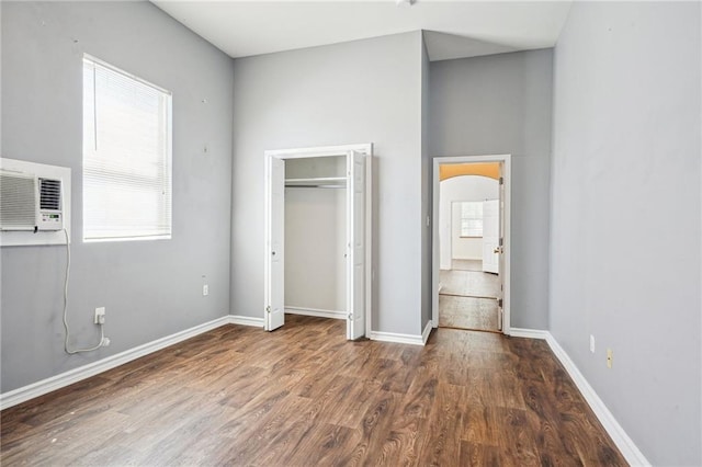 320709 Bienville St, New Orleans, LA 70119 - unfurnished bedroom with arched walkways, a closet, wood finished floors, an AC wall unit, and baseboards