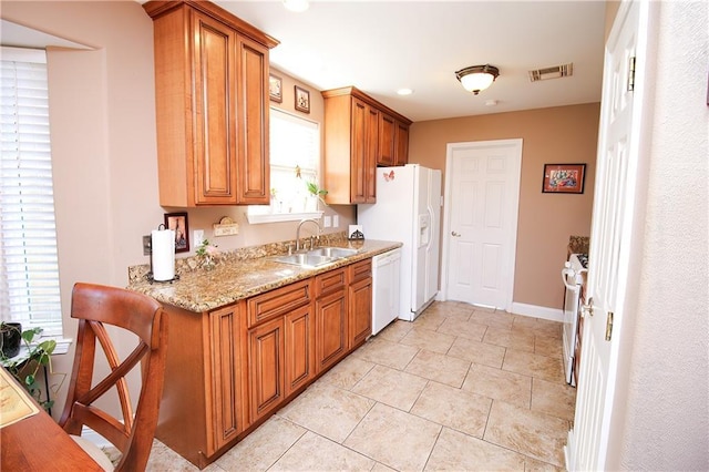 4504 Stella Dr, Meraux, LA 70075 - kitchen with visible vents, light stone counters, brown cabinets, white appliances, and a sink