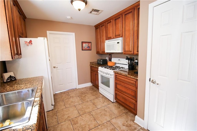 4504 Stella Dr, Meraux, LA 70075 - kitchen with white appliances, dark stone countertops, visible vents, a sink, and brown cabinets