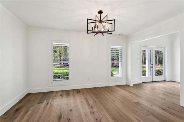 unfurnished dining area with a chandelier, wood finished floors, baseboards, crown molding, and french doors