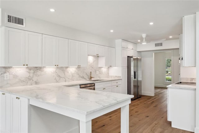 kitchen with stainless steel appliances, a sink, a peninsula, white cabinetry, and recessed lighting