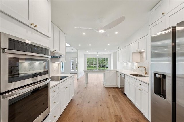 kitchen featuring appliances with stainless steel finishes, a sink, light countertops, tasteful backsplash, and white cabinetry