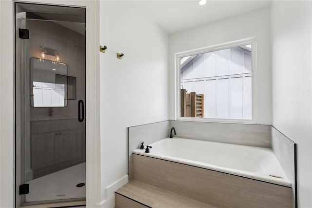 full bathroom featuring a shower stall, a garden tub, and baseboards