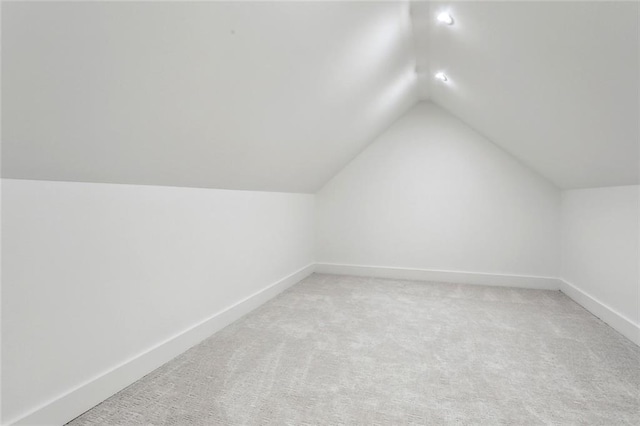 bonus room featuring baseboards, vaulted ceiling, and light colored carpet