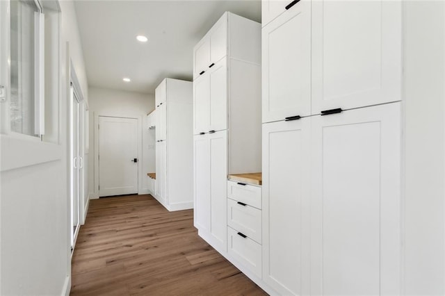 corridor with wood finished floors, recessed lighting, and baseboards