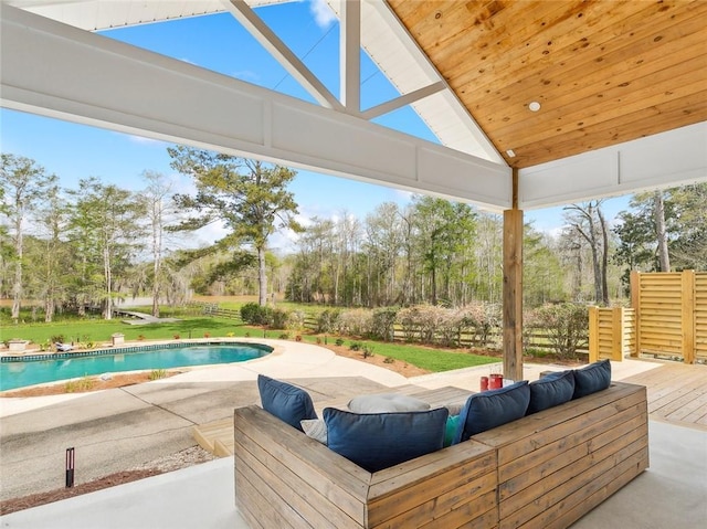 outdoor pool with view of wooded area, a patio area, and a lawn