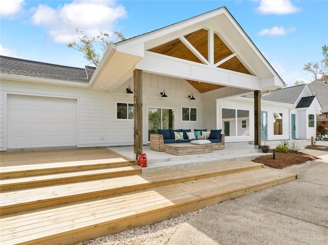back of house featuring outdoor lounge area, a garage, a deck, and roof with shingles
