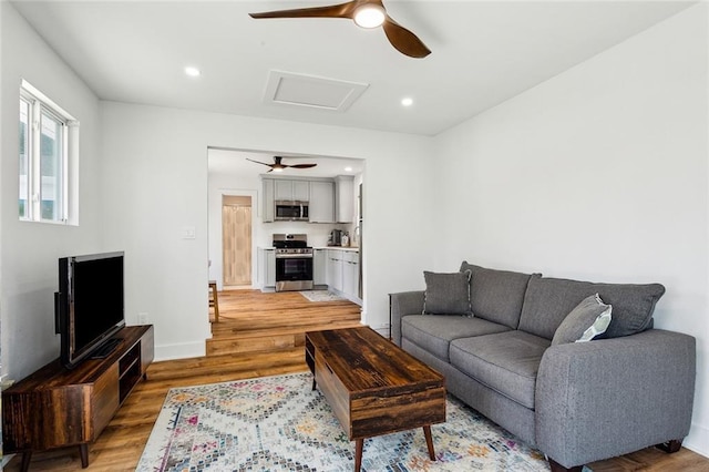 living room with a ceiling fan, light wood-style flooring, attic access, recessed lighting, and baseboards