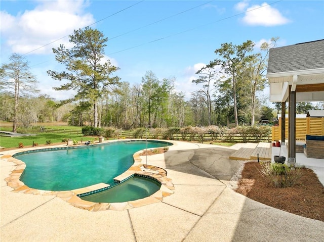 view of swimming pool with fence, a patio, and a pool with connected hot tub