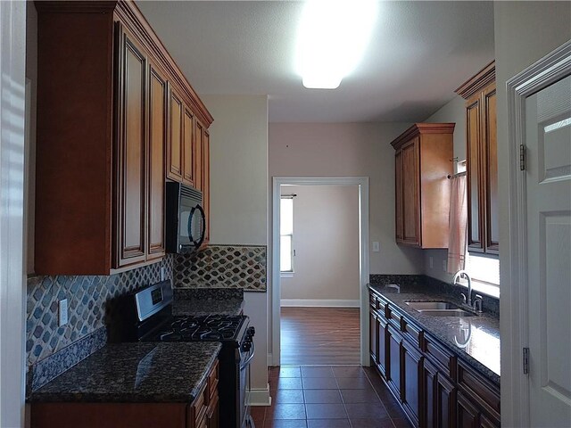 4800 Eastview Dr, New Orleans, LA 70126 - kitchen with gas range, decorative backsplash, dark stone counters, a sink, and black microwave