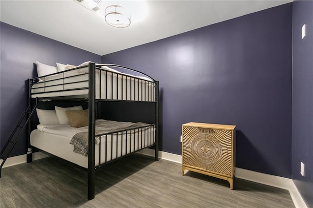 bedroom featuring visible vents, baseboards, and wood finished floors