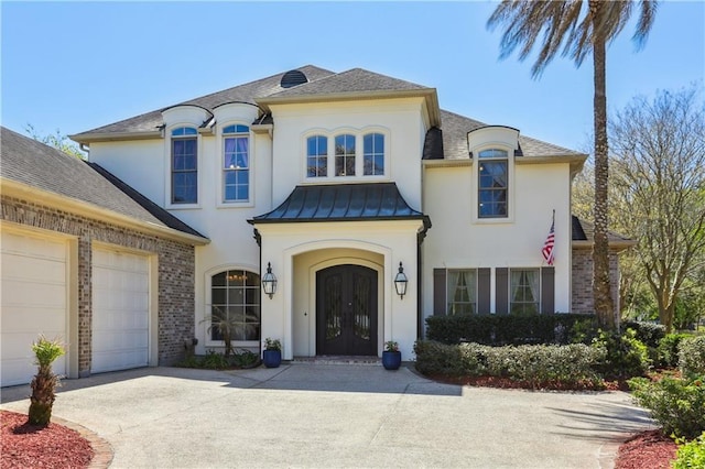 192 Forest Oaks Dr, New Orleans, LA 70131 - view of front of home with stucco siding, a standing seam roof, driveway, and french doors