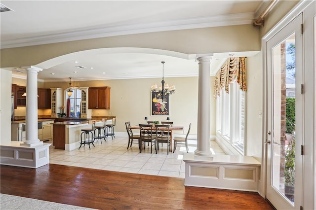 192 Forest Oaks Dr, New Orleans, LA 70131 - dining space featuring ornate columns, an inviting chandelier, light wood-style flooring, arched walkways, and crown molding