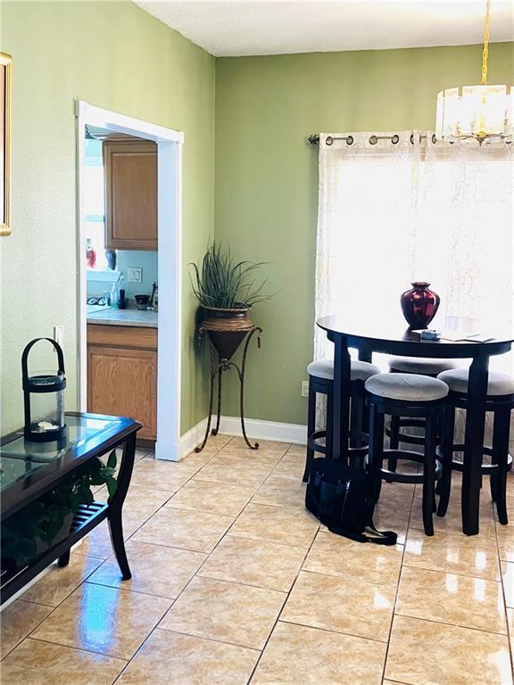 dining room with light tile patterned floors, baseboards, and a chandelier
