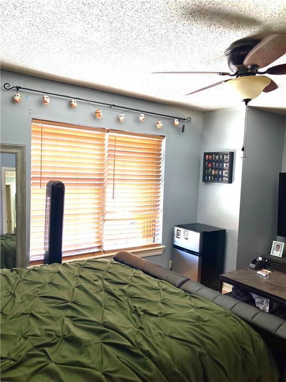 bedroom featuring multiple windows, a textured ceiling, and freestanding refrigerator