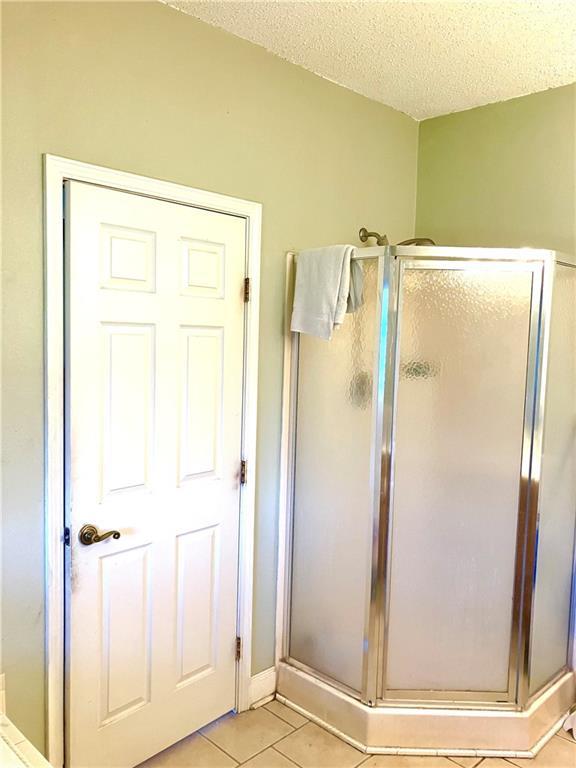 full bathroom with tile patterned floors, a stall shower, and a textured ceiling