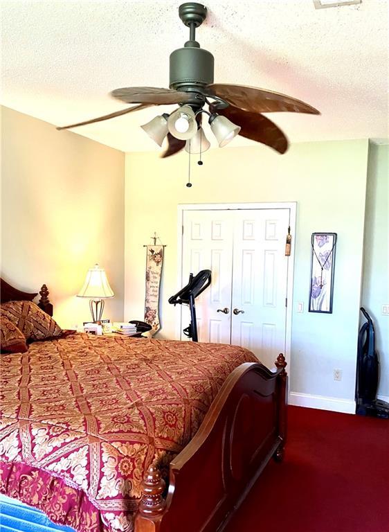 bedroom featuring baseboards, a textured ceiling, and ceiling fan