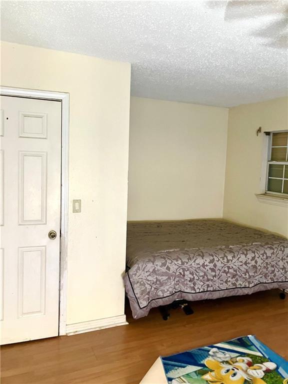 bedroom with a textured ceiling and wood finished floors