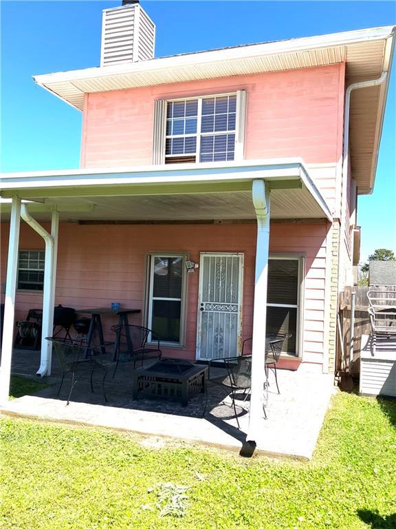 back of property with covered porch and a chimney